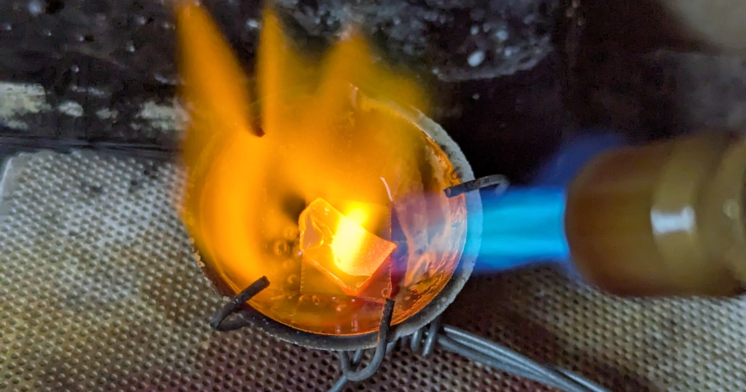 Zdjęcie przedstawia proces topienia złota w tyglu